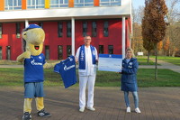 Das Maskottchen von Schalke 04 überreicht ein Trikot und Natascha Schwenzfeier von der Stiftung "Schalke hilft" den Spendenscheck an Dr. Gerrit Lautner.